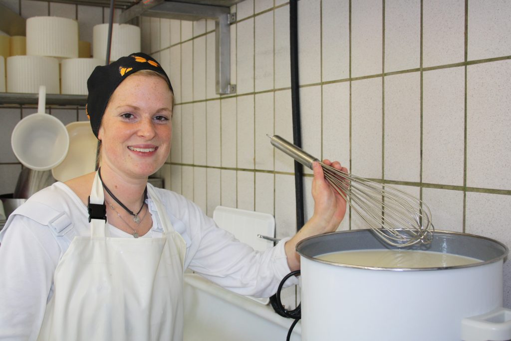 Sophie, Käserin auf dem Biobauernhof Braun, mit einem großen Topf der wertvollen Rohmilch.